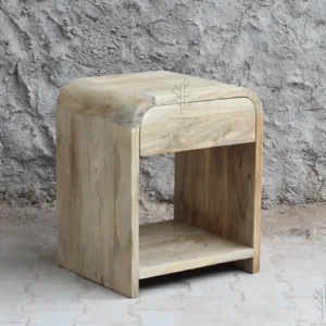 Siguiendo la línea orgánica de la colección Ibiza, esta mesita de noche en madera de mango color natural destaca por sus formas redondeadas